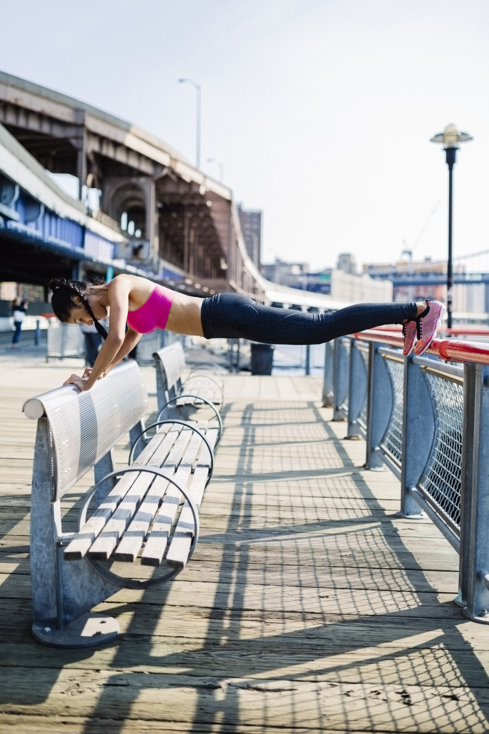 Female athlete training in Manhattan near Brooklyn Bridge, doing push ups on railing