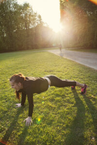 Young woman doing push-ups on grassy field in park